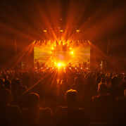 Do palco ao público: palco repleto de pessoas com luz amarelada no ambiente