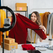 Liveshop Black Friday: mulher branca segurando uma blusa vermelha na frente de um ringlight